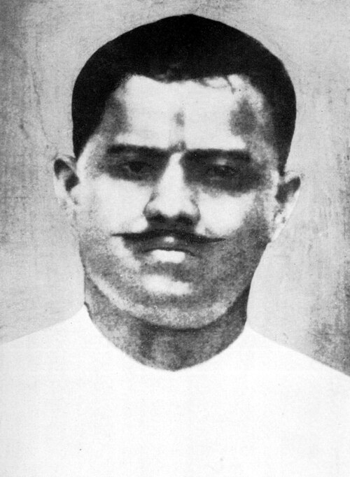Archival black-and-white photographic portrait of Ram Prasad Bismil as a young man, wearing a white collarless kurta, a tilak mark on his forehead.